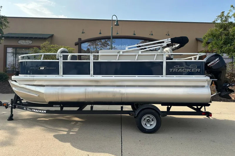 The Image of 2026 Sun Tracker Bass Buggy 18 DLX pontoon boat on trailer, parked outdoors. - 0