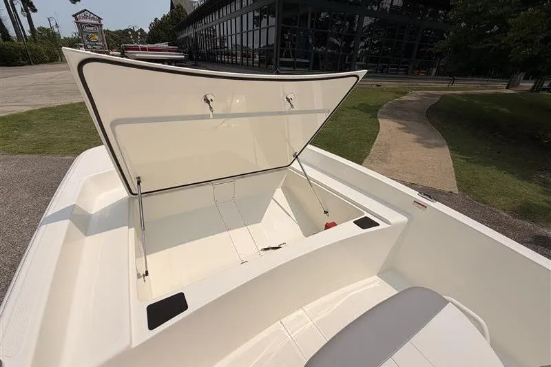 Slide: The Image of 2026 Mako Pro Skiff 17 CC boat with open storage compartment, outdoor setting. - 7