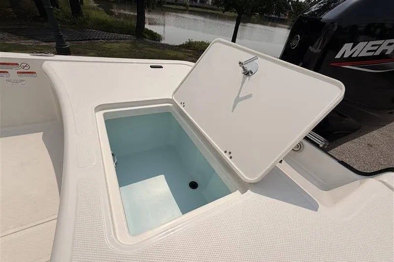 Slide: The Image of Open storage compartment on 2026 Mako Pro Skiff 17 CC boat, near water. - 14
