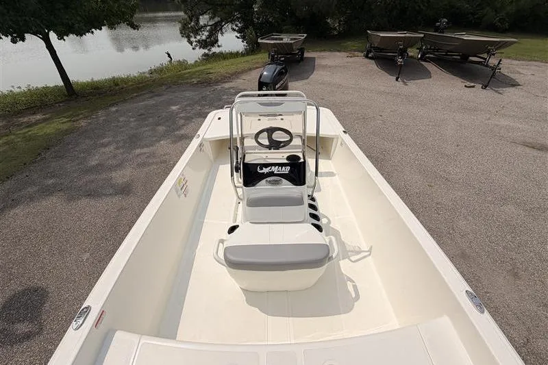 Slide: The Image of 2026 Mako Pro Skiff 17 CC boat parked near a serene lakeside. - 5