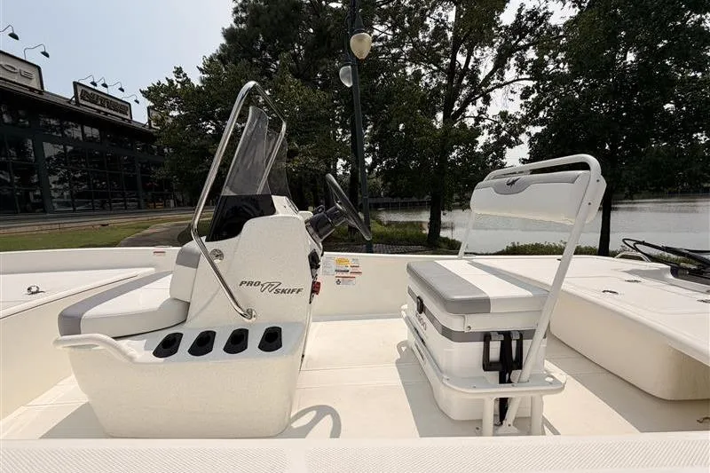 Slide: The Image of 2026 Mako Pro Skiff 17 CC boat interior with console and seating, near a waterfront. - 10