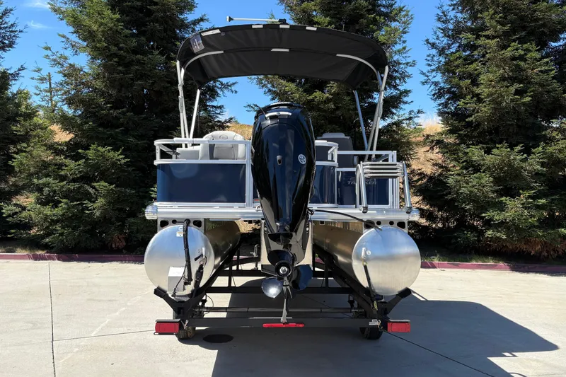 Slide: The Image of 2026 Sun Tracker Bass Buggy 18 DLX pontoon boat on trailer, surrounded by trees. - 7