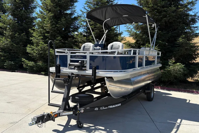 Slide: The Image of 2026 Sun Tracker Bass Buggy 18 DLX pontoon boat on trailer, parked outdoors. - 10