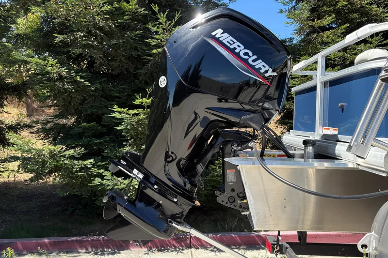 Slide: The Image of 2026 Sun Tracker Bass Buggy 18 DLX with Mercury outboard motor in a wooded setting. - 29