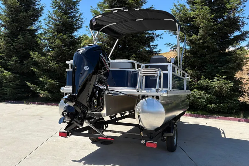 Slide: The Image of 2026 Sun Tracker Bass Buggy 18 DLX pontoon boat with outboard motor, parked outdoors. - 9