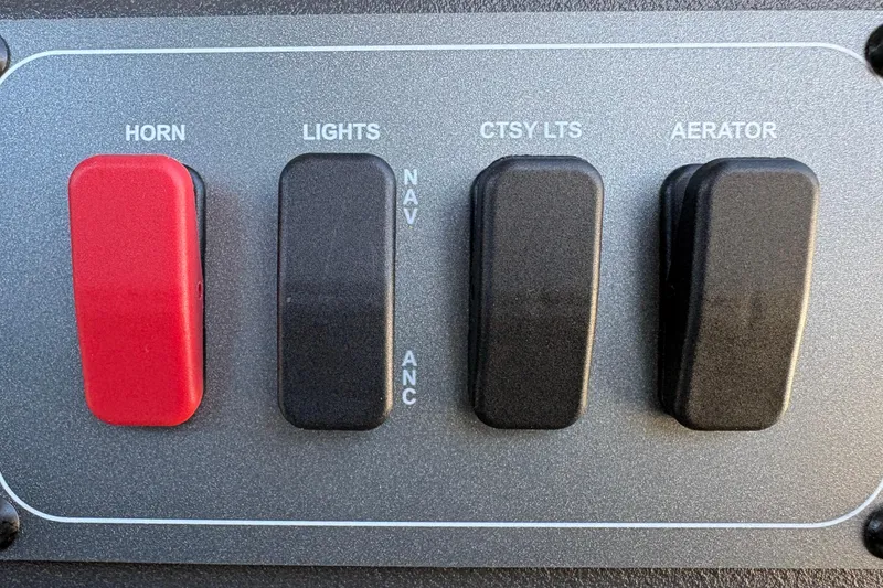 Slide: The Image of Control panel of 2026 Sun Tracker Bass Buggy 18 DLX with switches for horn, lights, and aerator. - 22