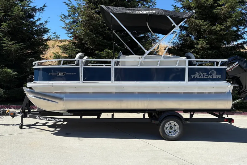 The Image of 2026 Sun Tracker Bass Buggy 18 DLX pontoon boat on trailer, parked outdoors. - 0