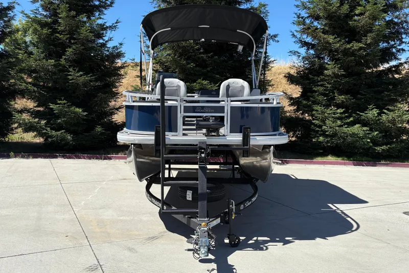 Slide: The Image of 2026 Sun Tracker Bass Buggy 18 DLX pontoon boat on trailer, parked outdoors. - 3