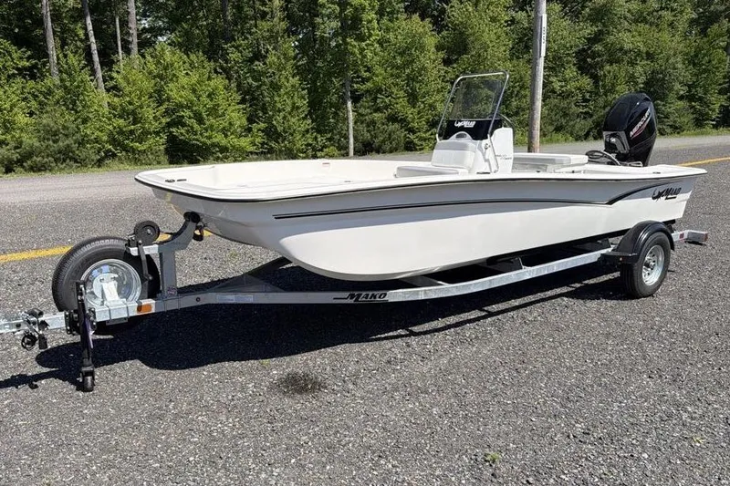 The Image of 2026 Mako Pro Skiff 17 CC boat on trailer, parked on roadside with forest background. - 0