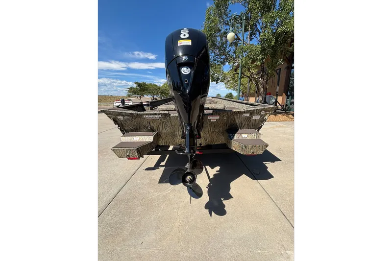 Slide: The Image of 2026 Tracker Grizzly 2072 CC boat with outboard motor, parked outdoors. - 13