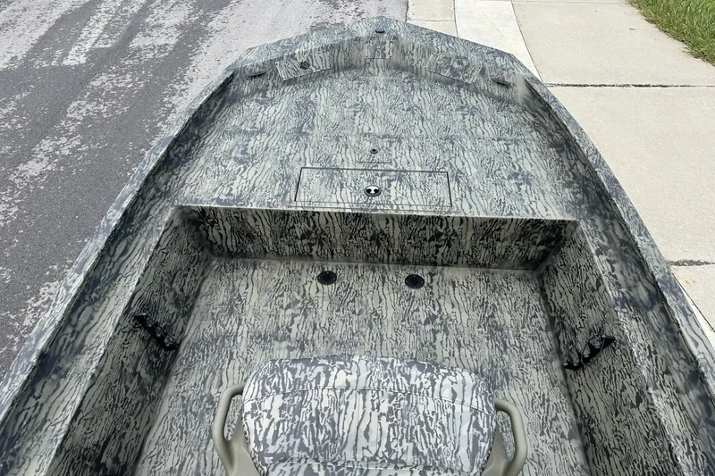 Slide: The Image of 2026 Tracker Grizzly 1860 CC boat interior with camouflage pattern, parked on a street. - 14
