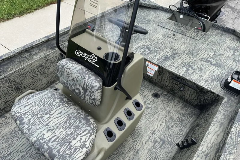 Slide: The Image of 2026 Tracker Grizzly 1860 CC boat interior with camouflage seating and steering console. - 19