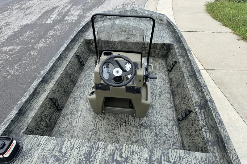 Slide: The Image of 2026 Tracker Grizzly 1860 CC boat with camouflage interior, parked on a street. - 13