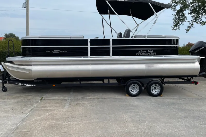 The Image of 2026 Sun Tracker Party Barge 24 XP3 pontoon boat on trailer, parked outdoors. - 0