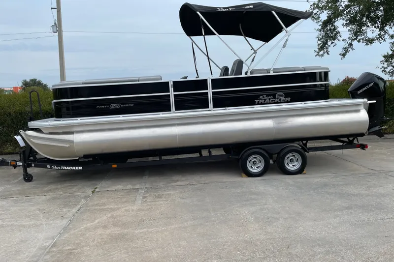 The Image of 2026 Sun Tracker Party Barge 24 XP3 pontoon boat on trailer, parked outdoors. - 0