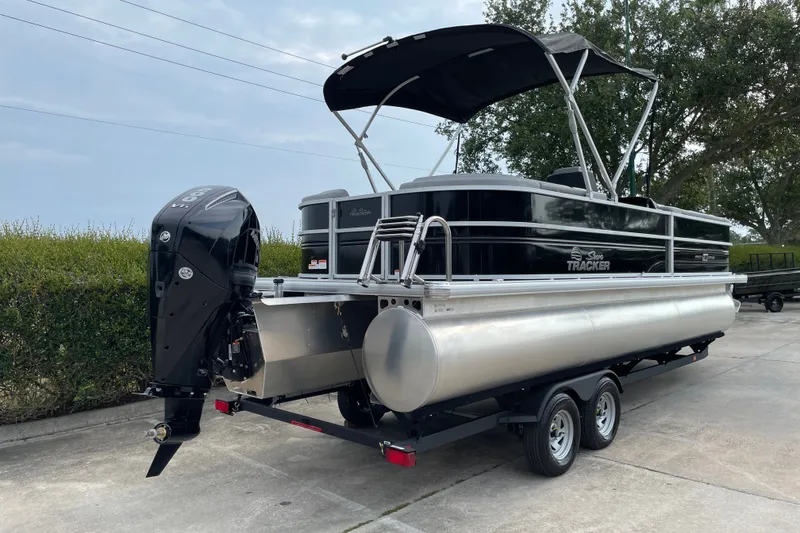 Slide: The Image of 2026 Sun Tracker Party Barge 24 XP3 pontoon boat on trailer, parked outdoors. - 5