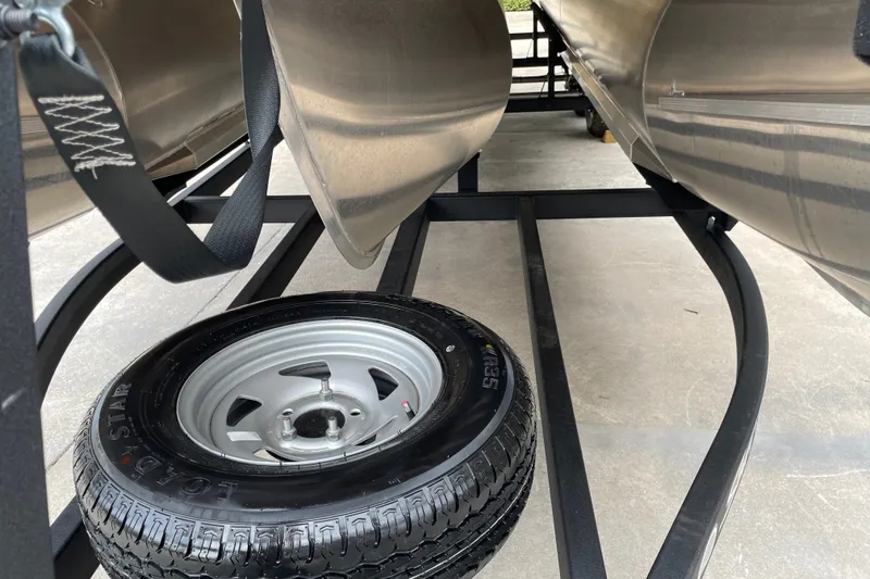 Slide: The Image of 2026 Sun Tracker Party Barge 24 XP3 trailer with spare tire underneath pontoons. - 8