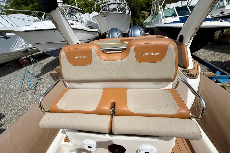 Slide: The Image of 2024 Zodiac Medline 9 boat interior with beige and brown seating, docked among other boats. - 16