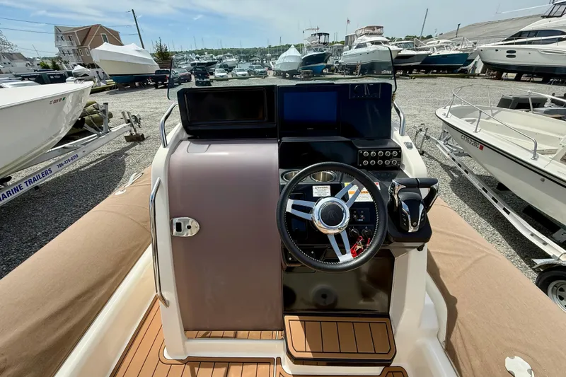 Slide: The Image of 2024 Zodiac Medline 9 boat dashboard with steering wheel and controls, docked among other boats. - 17
