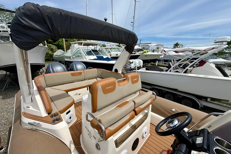 Slide: The Image of 2024 Zodiac Medline 9 boat interior with cushioned seating and steering wheel, docked among other boats. - 25
