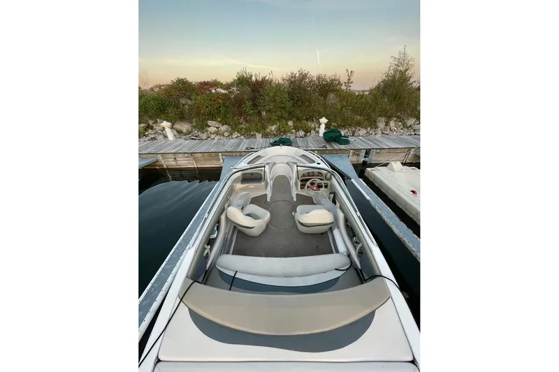 Slide: The Image of 1999 Four Winns 180 Horizon boat docked, showcasing interior seating and steering wheel. - 1