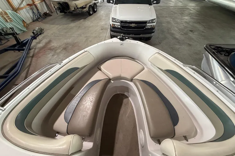 Slide: The Image of 1999 Four Winns 180 Horizon boat interior with cushioned seating in a garage. - 15