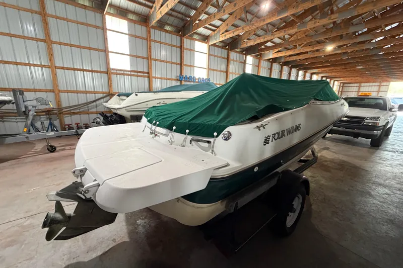 Slide: The Image of 1999 Four Winns 180 Horizon boat with green cover in a storage facility. - 5