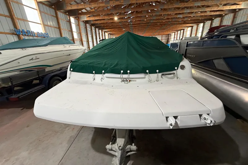 Slide: The Image of 1999 Four Winns 180 Horizon boat with green cover in storage facility. - 6