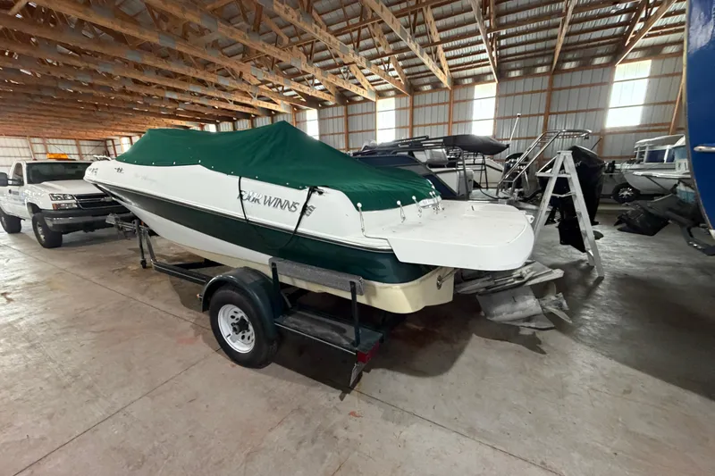Slide: The Image of 1999 Four Winns 180 Horizon boat with green cover in storage facility. - 7