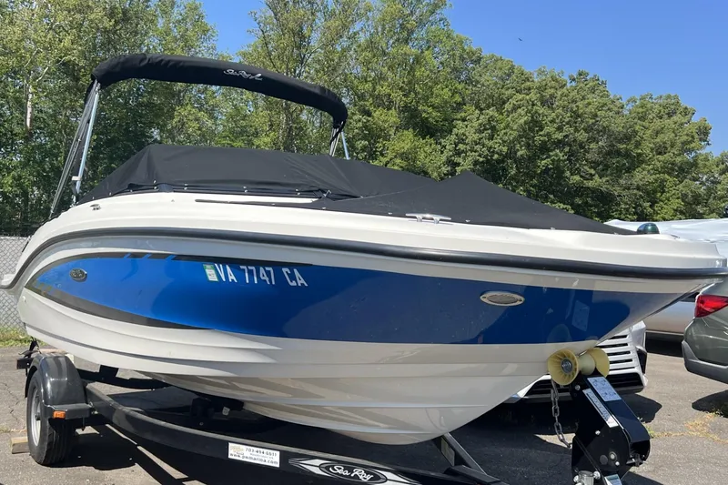 The Image of 2016 Sea Ray SPX 190 boat with blue hull on trailer, parked outdoors. - 0