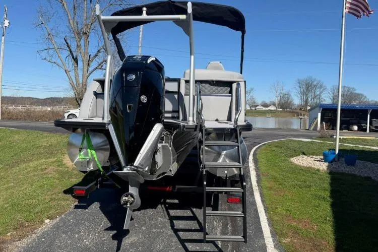 Slide: The Image of 2026 South Bay 523RS pontoon boat with outboard motor, parked near a lake. - 1