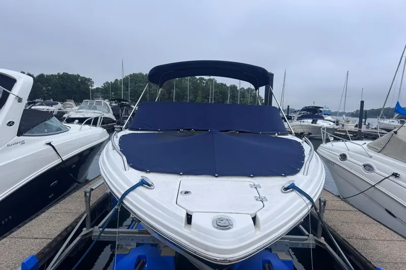 Slide: The Image of 2021 Chaparral 237 SSX boat docked with blue cover, surrounded by other boats. - 1