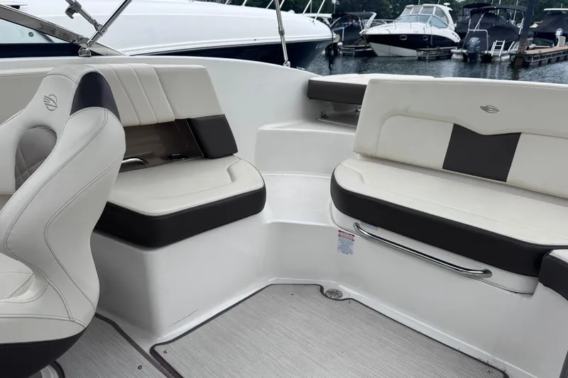 Slide: The Image of 2021 Chaparral 237 SSX boat interior with white and black seating at a marina. - 10