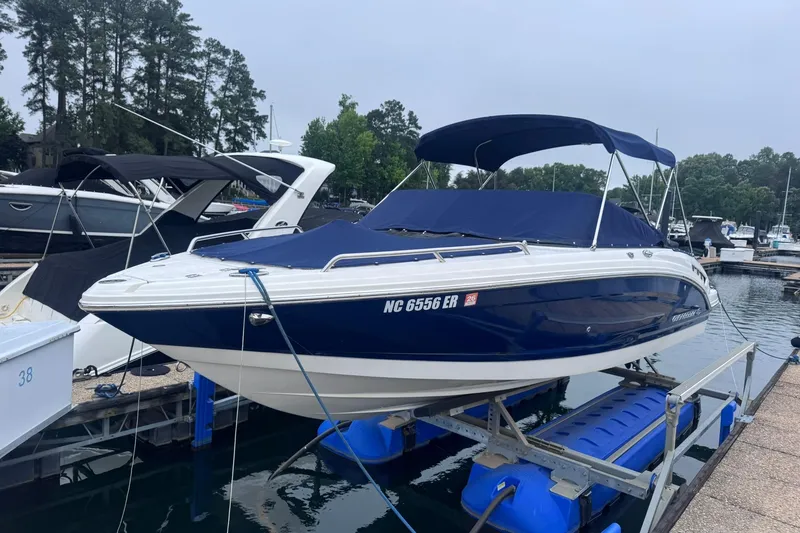 Slide: The Image of 2021 Chaparral 237 SSX boat docked, featuring a sleek blue and white design with a canopy. - 2