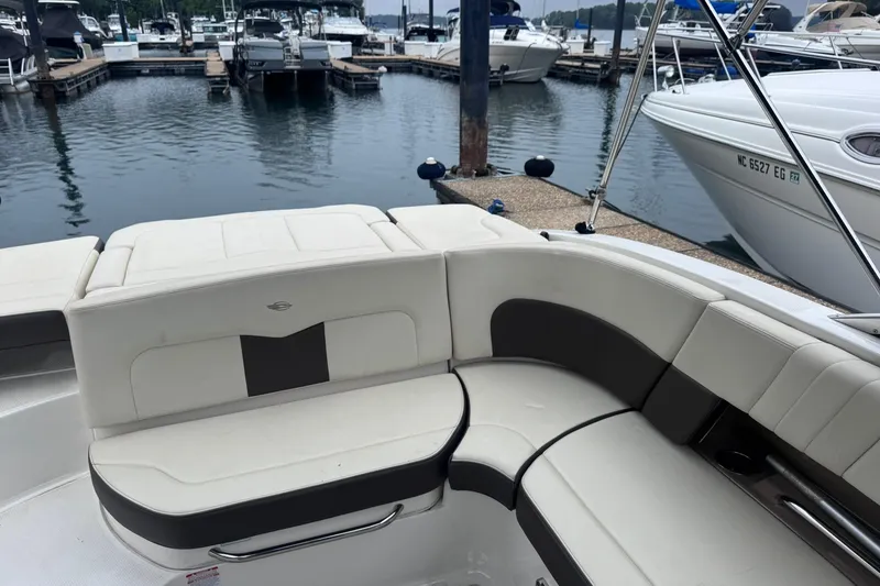 Slide: The Image of 2021 Chaparral 237 SSX boat interior with white and black seating at a marina. - 4