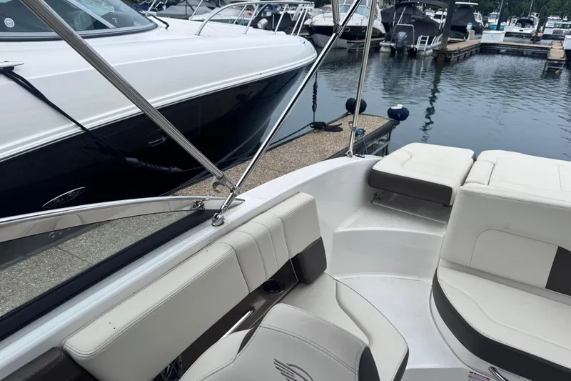 Slide: The Image of 2021 Chaparral 237 SSX boat interior at marina, featuring white seating and sleek design. - 5