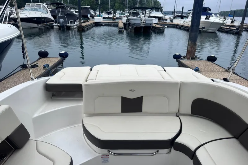 Slide: The Image of 2021 Chaparral 237 SSX boat interior at marina, featuring comfortable seating and docked boats. - 6
