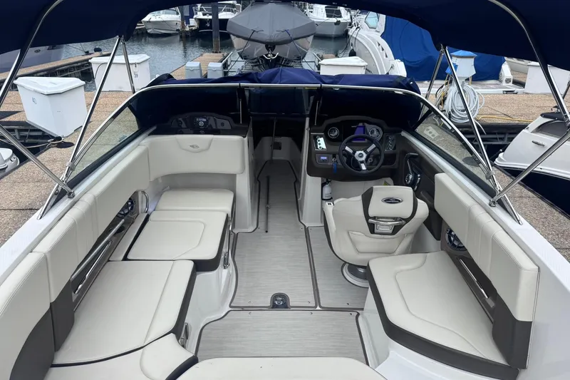 Slide: The Image of 2021 Chaparral 237 SSX boat interior with seating and steering wheel at a marina. - 8