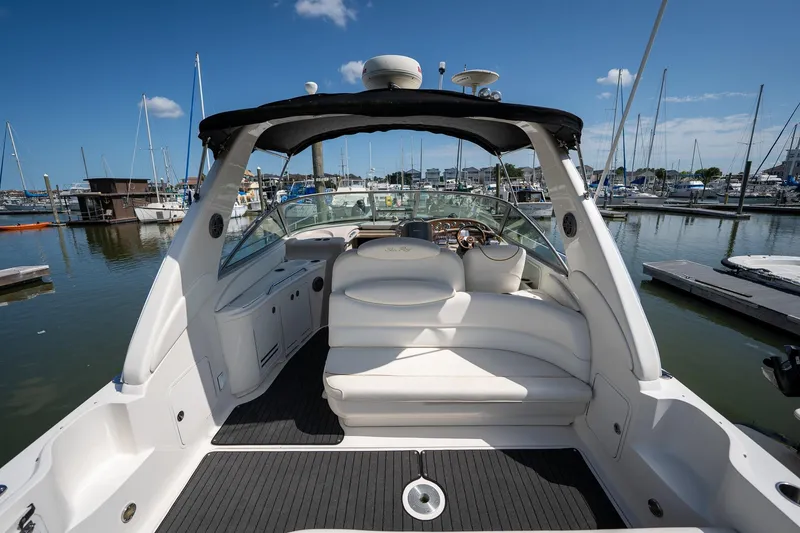 Slide: The Image of 2000 Sea Ray 340 Sundancer boat interior at marina, featuring white seating and helm. - 6