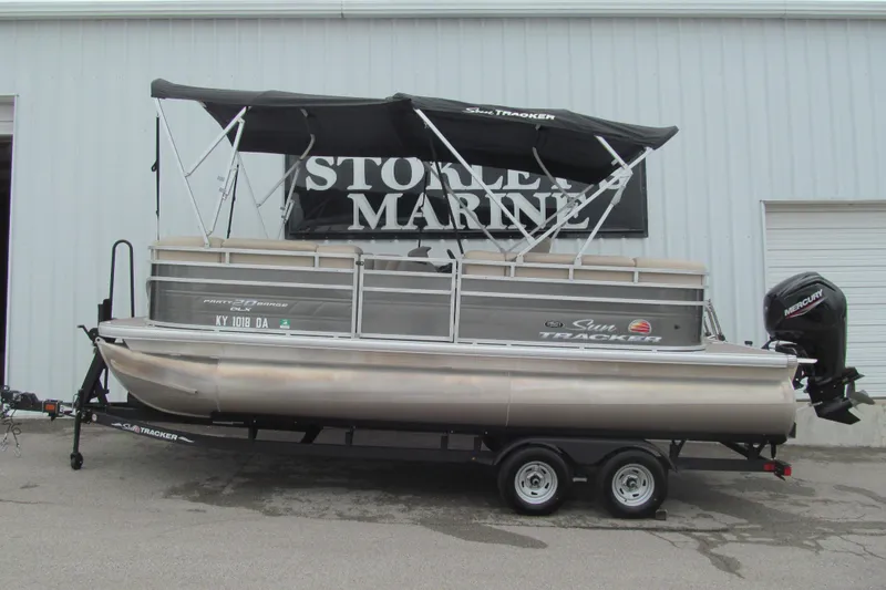 The Image of 2024 Sun Tracker Party Barge 20 DLX pontoon boat on trailer, with canopy and Mercury outboard. - 0