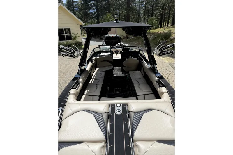 Slide: The Image of 2023 Centurion Fi25 boat interior with luxurious seating and sleek design in a wooded setting. - 4