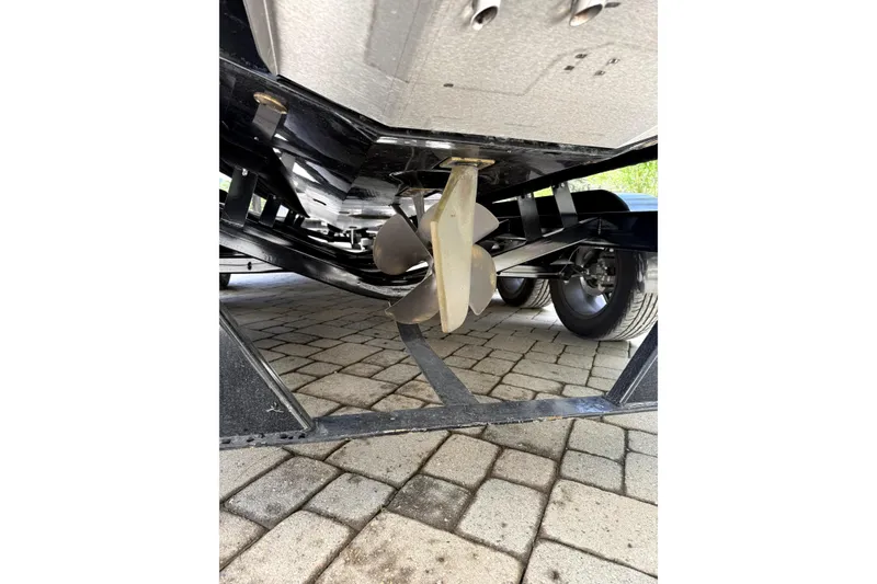 Slide: The Image of Underneath view of 2023 Centurion Fi25 boat showing propeller and trailer on paved surface. - 5