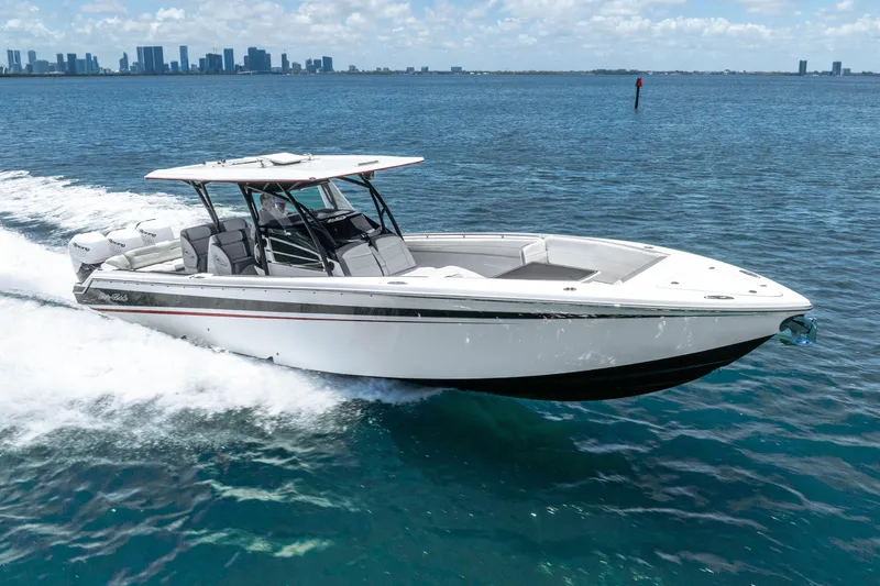 Slide: The Image of 2019 Nor-Tech 390 Sport Center Console cruising on open water with city skyline backdrop. - 8