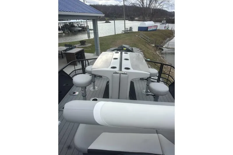 Slide: The Image of 2026 SunChaser Eclipse 25 SBX DH BAR pontoon boat with bar seating, docked by a lakeside. - 14