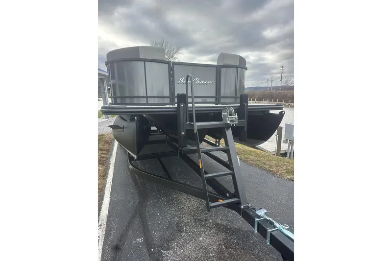 Slide: The Image of 2026 SunChaser Eclipse 25 SBX DH BAR pontoon boat on trailer under cloudy sky. - 2
