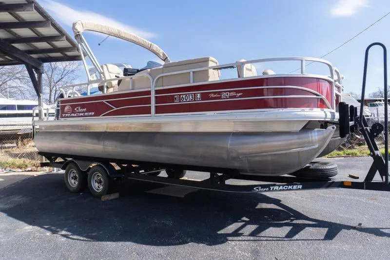 The Image of 2019 Sun Tracker Fishin' Barge 22 DLX pontoon boat on trailer, parked outdoors. - 0