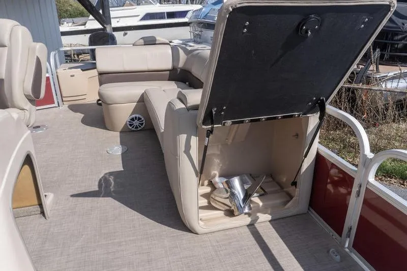 Slide: The Image of 2019 Sun Tracker Fishin' Barge 22 DLX interior with open storage compartment and beige seating. - 16