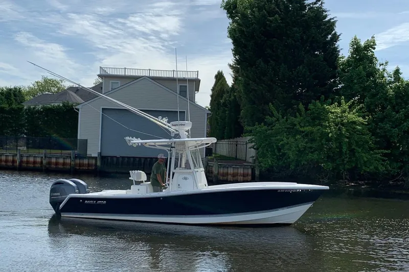 Slide: The Image of 2006 Regulator 24 Classic boat on a calm river near a house and trees. - 22