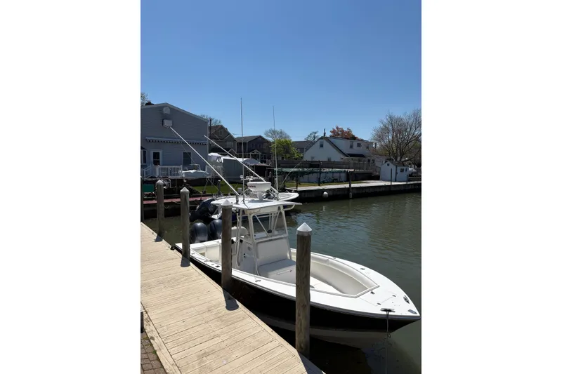 Slide: The Image of 2006 Regulator 24 Classic boat docked by waterfront homes under clear blue sky. - 23