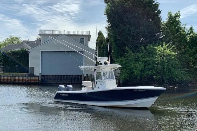 Slide: The Image of 2006 Regulator 24 Classic boat cruising on a calm river near a boathouse. - 25